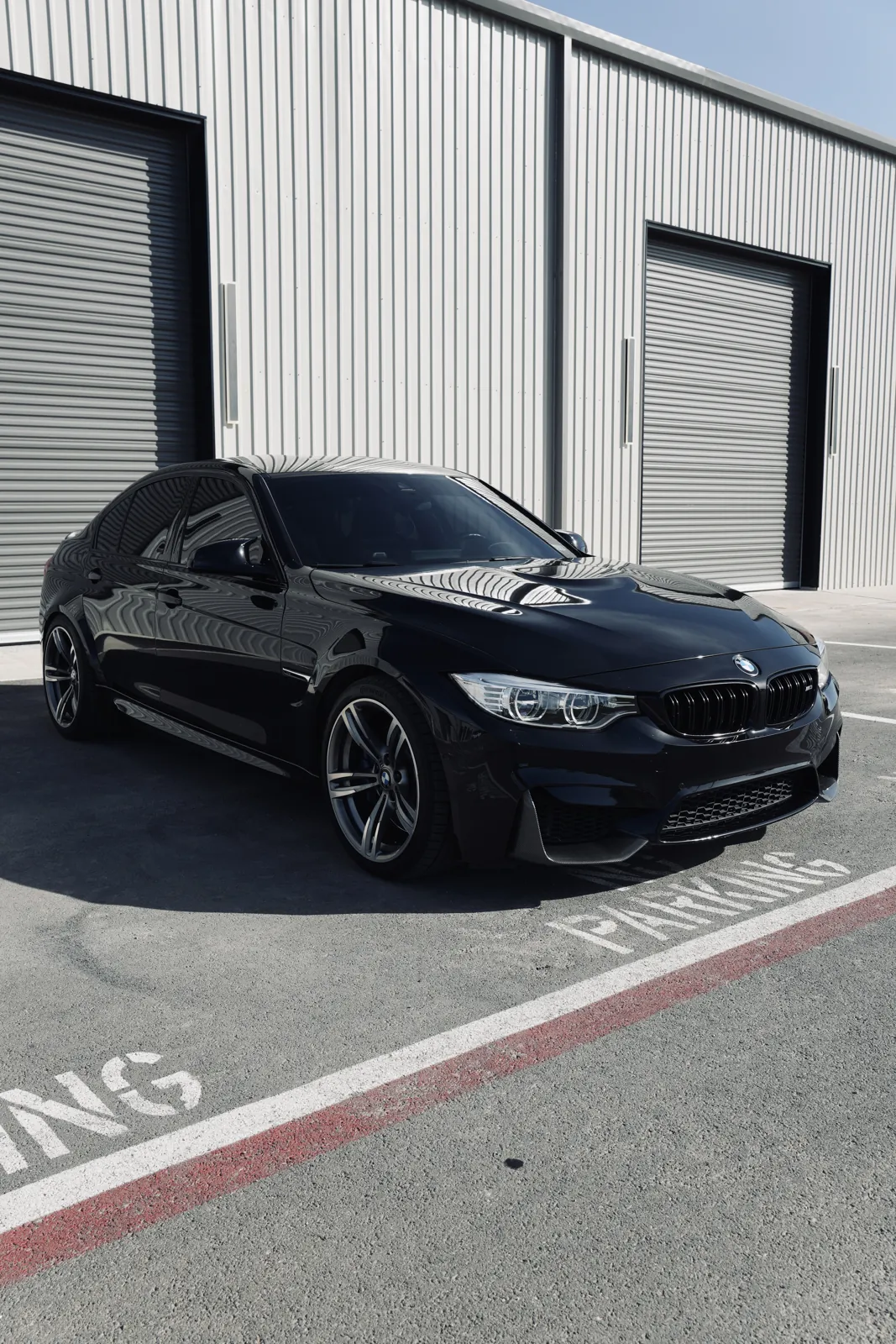 Blacked-out BMW M4 with dark window tint parked outside the shop