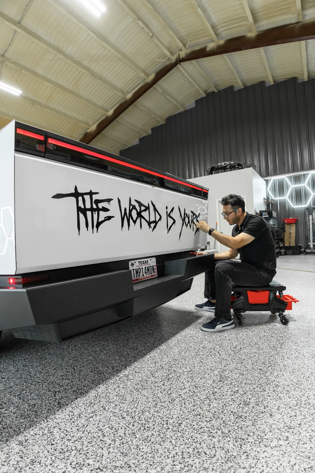Custom graffiti-style decal being applied to a Cybertruck bed side in the shop