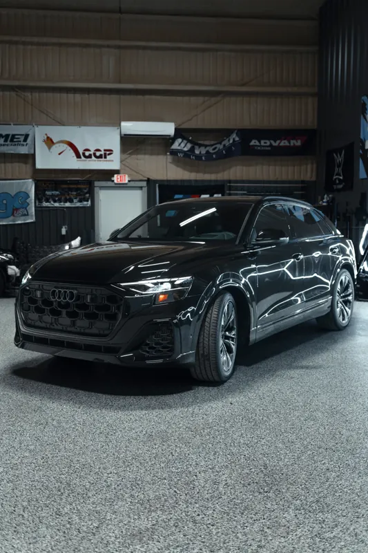 Blacked-out Audi Q8 under hex lights in the shop