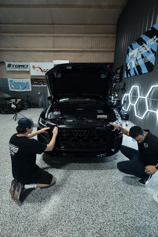 Two installers in Resendiz shirts at the front of the Audi Q8